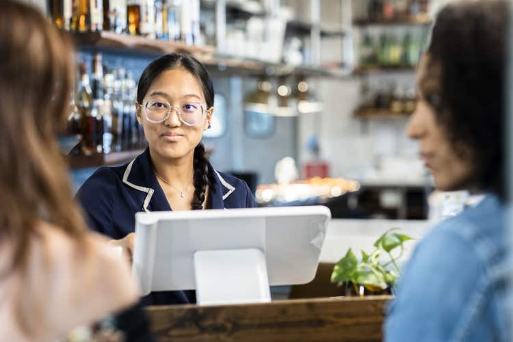 femme accueillant les clients d'un restaurant à l'aide d'une Clover Station Solo