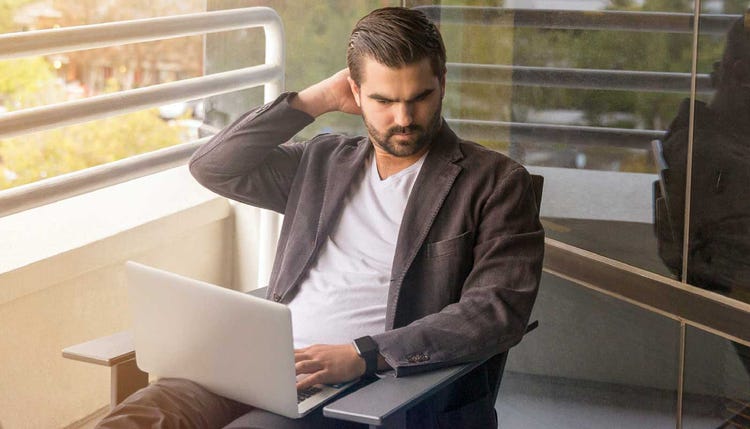 Homme regardant un ordinateur portable sur un balcon