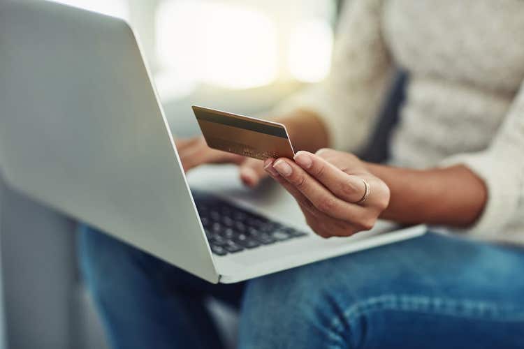 Femme tenant une carte de crédit en utilisant un ordinateur portable