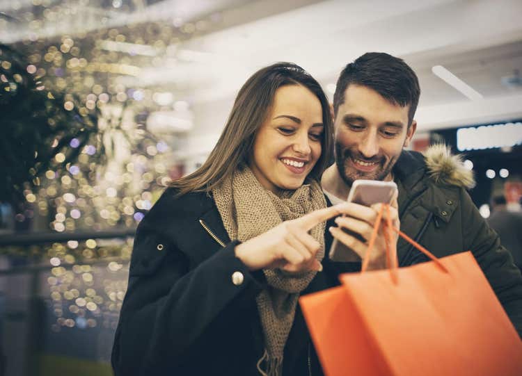 Couple regardant un téléphone portable en faisant du shopping