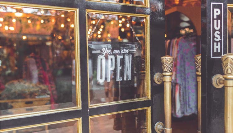 Enseigne ouverte accrochée à la vitrine de la boutique