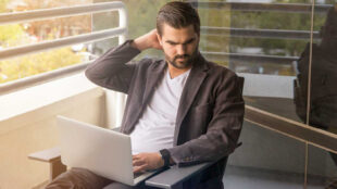 Homme regardant un ordinateur portable sur un balcon