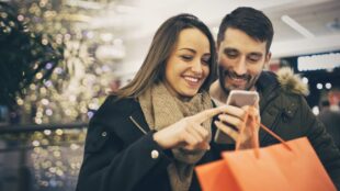 Couple regardant un téléphone portable en faisant du shopping