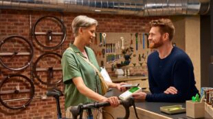 Une femme dans un magasin de vélos effectuant un paiement sur un terminal de paiement Clover Flex.