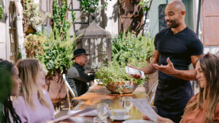 Un serveur prend la commande des clients à leur table, sur la terrasse.