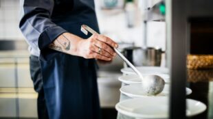 Un chef en train de servir des bols de soupe dans la cuisine d'un restaurant