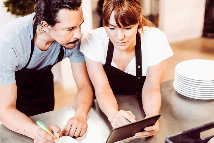 Woman and man looking at a tablet in a restaurant kitchen