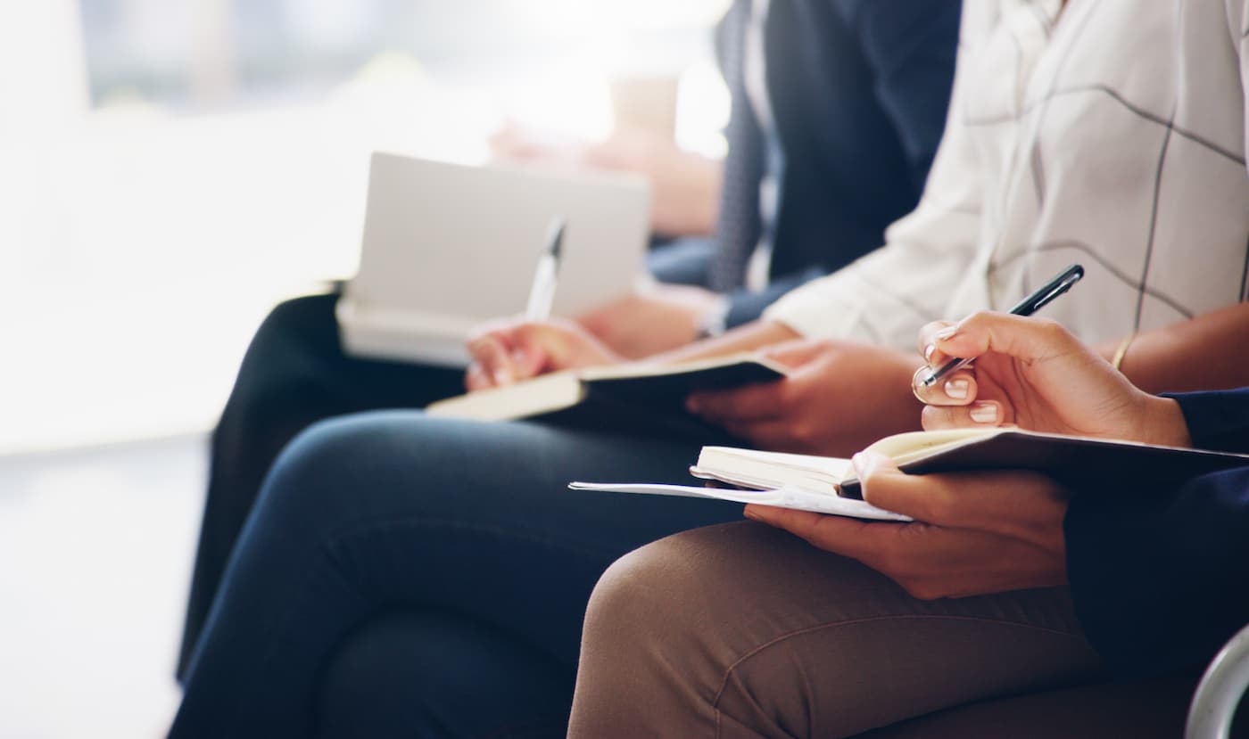 Cropped shot of unrecognizable businesspeople sitting and writing notes in a book while in the office during the day.