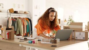 Female business owner working on her laptop and managing stock inside her boutique