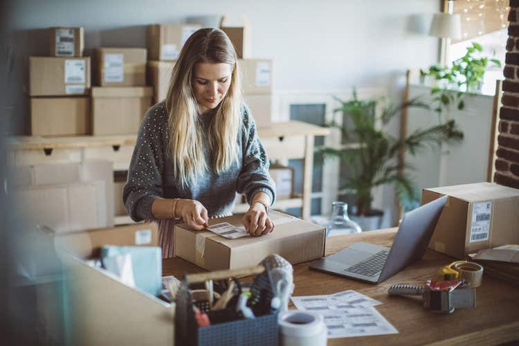 Woman applying shipping label to box