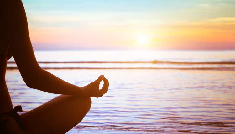 Person meditating near water