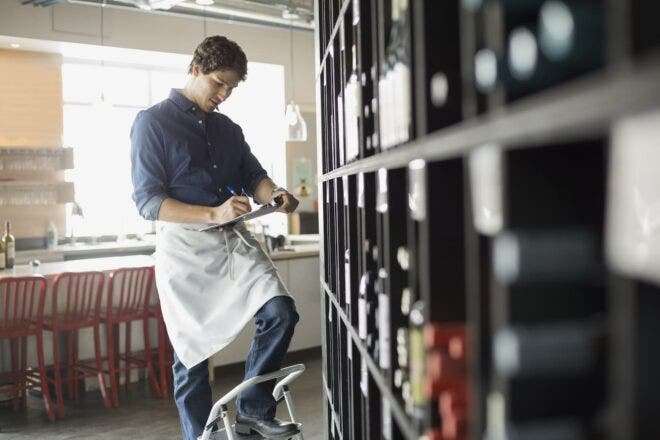 Wine shop owner writing on clipboard