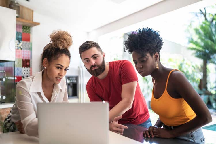 Three people looking at laptop