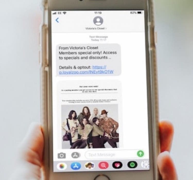 Person holding mobile phone with loyalty text message displaying