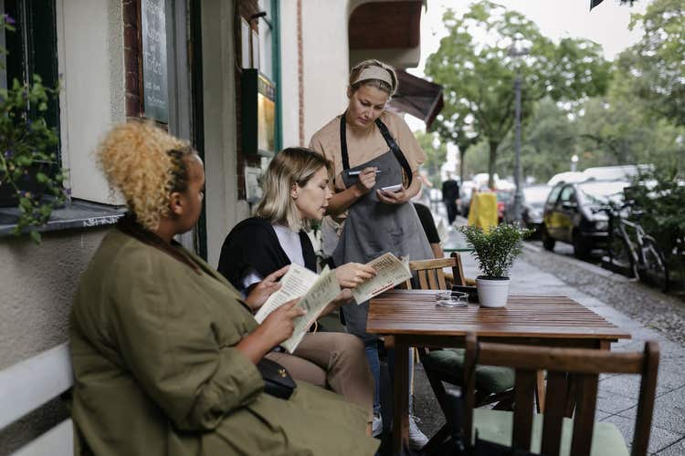 Waitress taking orders from two women holding menus