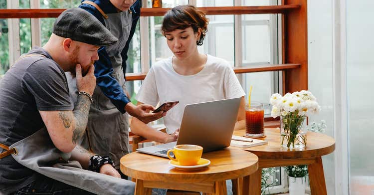 Restaurant employees looking at laptop and phone