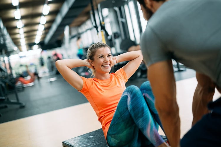Woman doing sit ups with personal trainer