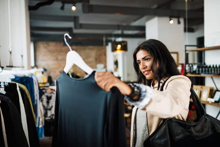 Woman holding up black shirt in store