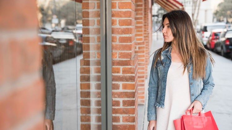 Woman with shopping bag walking past store