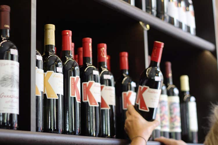 Person pulling bottle of wine from shelf