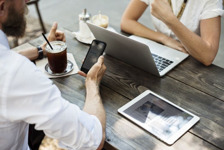 Two people on phone and laptop