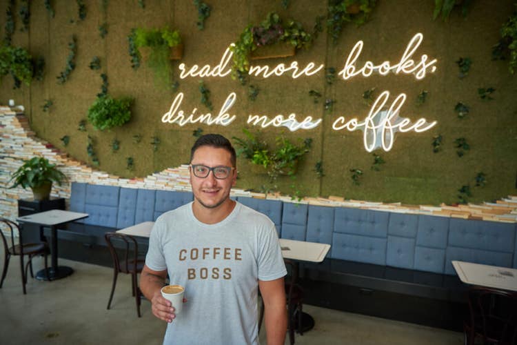 owner of winfield steet coffee standing in front of a sign in his shop
