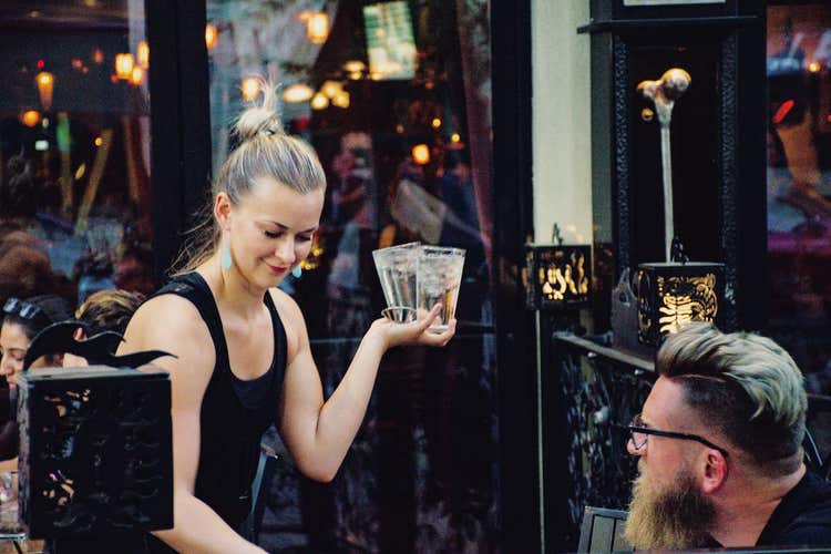 Restaurant server bringing glasses to table