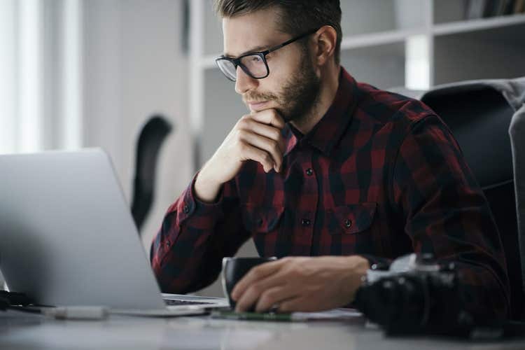 Man resting chin on hand looking at laptop