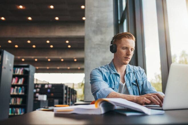Young man in library working on laptop
