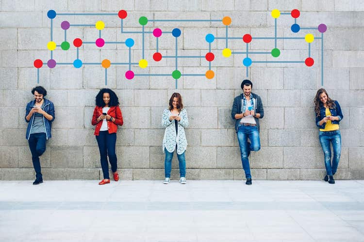 People standing against wall on smartphones