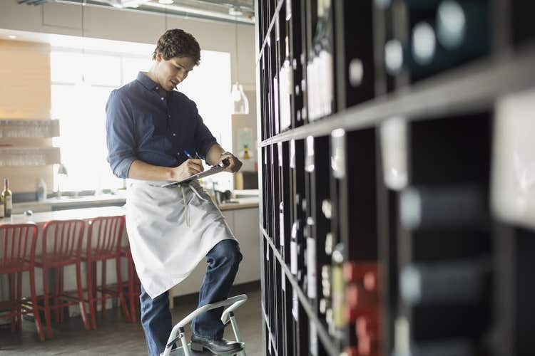 Wine shop owner writing on clipboard