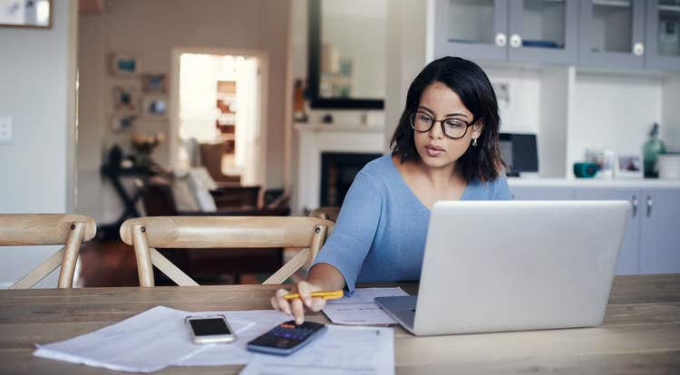 Woman with calculator, paperwork, and laptop