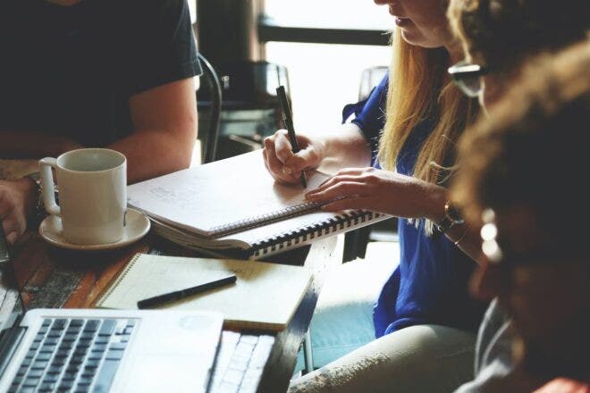 Person writing in notebook during employee training