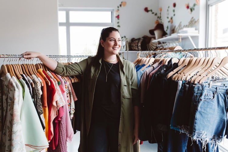 Woman standing by clothes racks in a shop