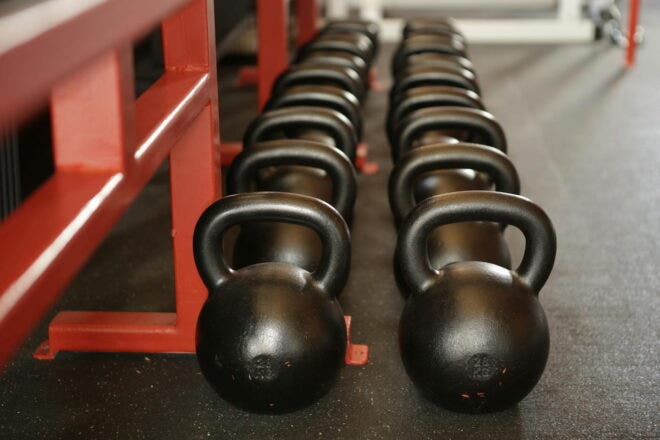Row of kettlebells lined up against a workout bench in a gym
