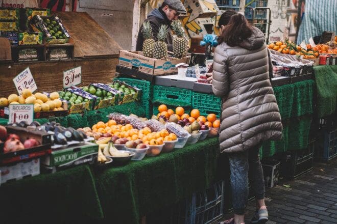 Woman buying produce at farmers market stand
