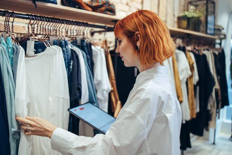 Retail shop owner looking at clothes on rack