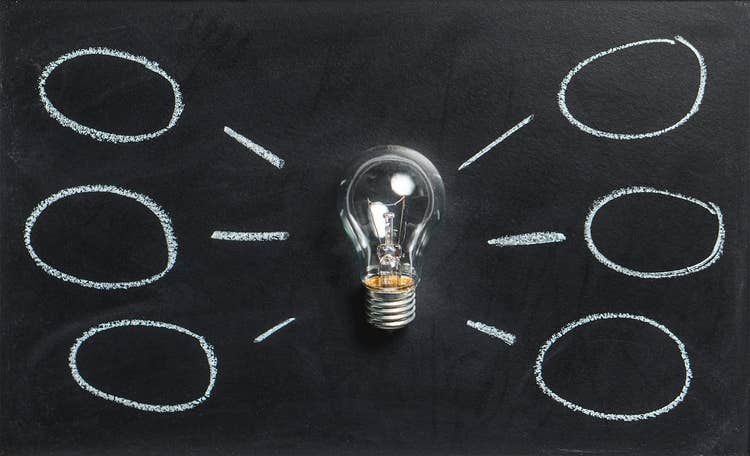 Glass light bulb and hand-drawn circles on black chalkboard background
