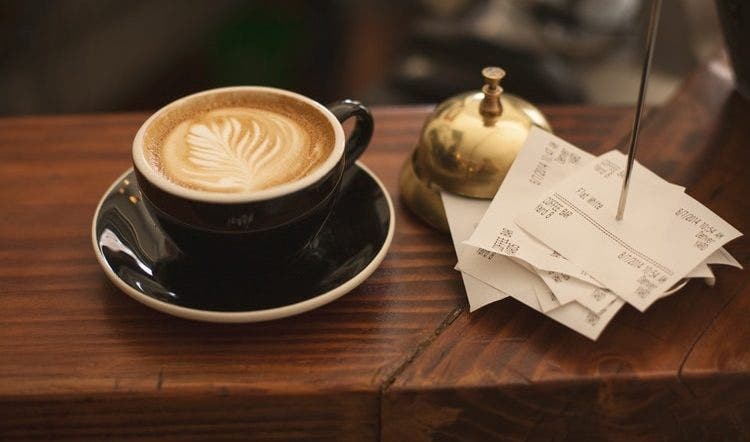 Coffee cup next to a bell on a counter
