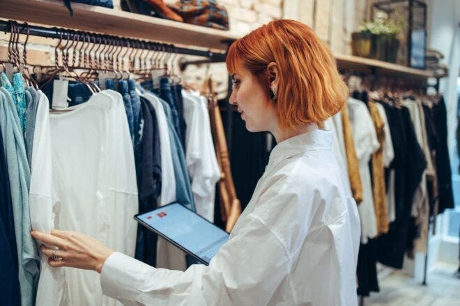 Retail shop owner looking at clothes on rack