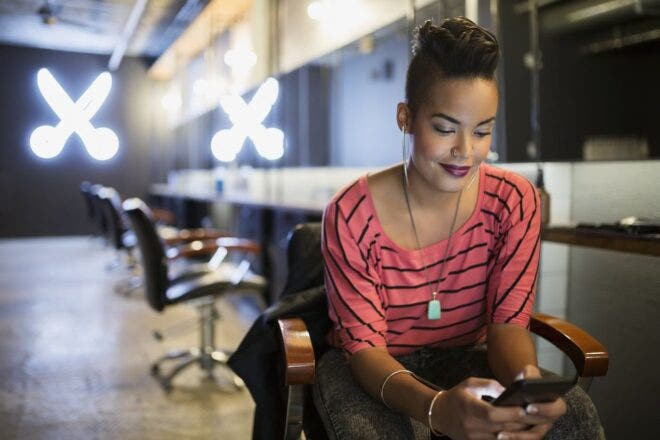 woman in salon chair looking at phone
