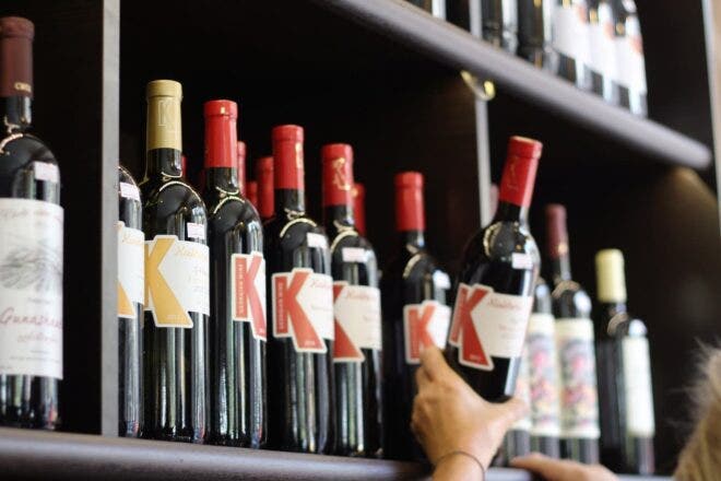Person pulling bottle of wine from shelf