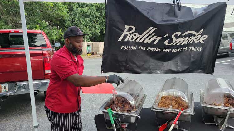 Rollin Smoke owner lifting lid on serving pan