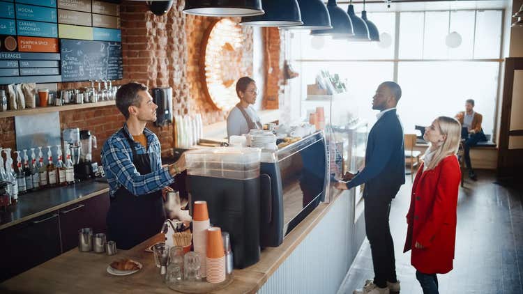Two baristas behind counter at coffee shop
