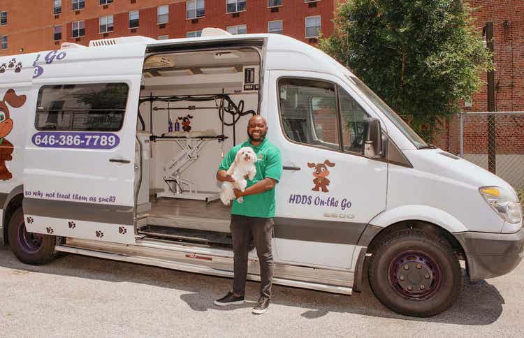 Man with dog in front of mobile grooming van
