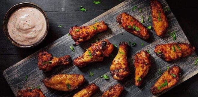 Wings and dipping sauce on a wooden platter from The Wing Suite