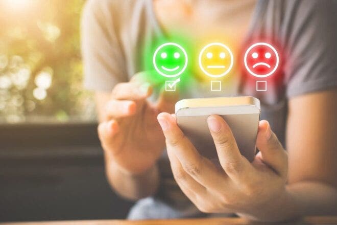 Person taking survey on phone with smileys above