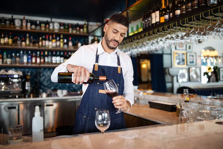 Bartender pouring glass of red wine