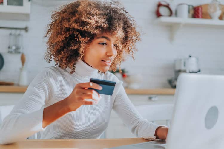 Woman holding credit card and using laptop