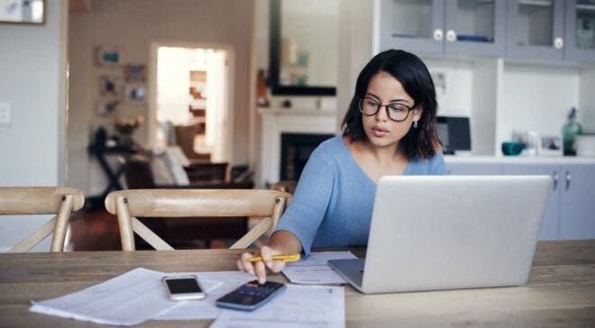 Woman with calculator, paperwork, and laptop